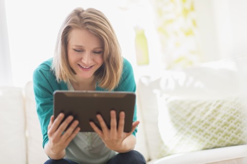 Portrait of woman on sofa using digital tablet.