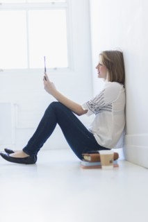 Young woman sitting on floor and using digital tablet.