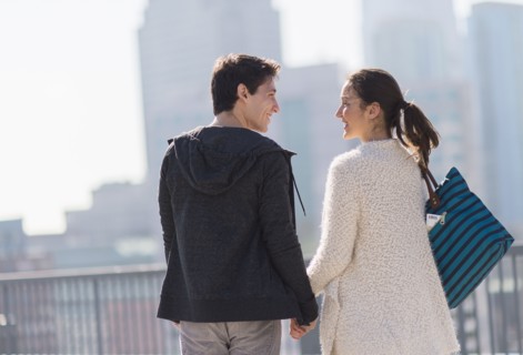 Young couple walking, buildings in background.
