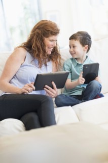Mother and son (6-7) using digital tablets.