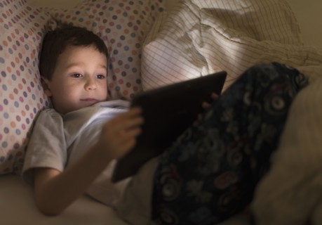 boy (6-7) using digital tablet in bed.