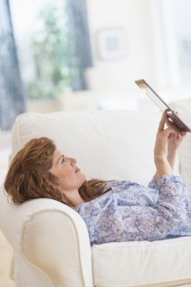 Woman lying on sofa and using laptop.