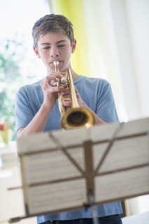 Teenage boy (16-17) playing trumpet.