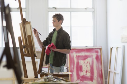Teenage boy (16-17) painting picture.