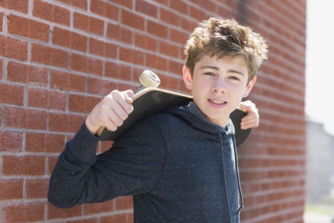 Teenage boy (16-17) holding skateboard.
