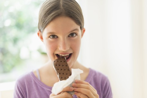 girl (10-11) eating ice cream sandwich.