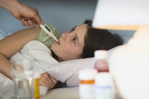 Sick girl (8-9) with thermometer in mouth.