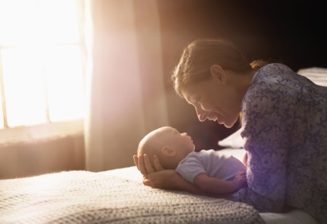 Mother holding baby boy (2-5 months) in bedroom.