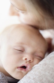 Close up of baby boy (2-5 months) sleeping on mother's shoulder.