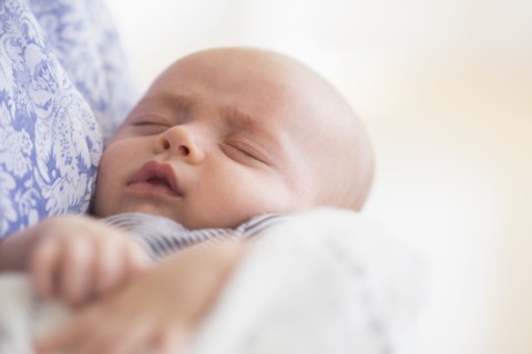 Close up of baby boy (2-5 months) sleeping in mother's arms.