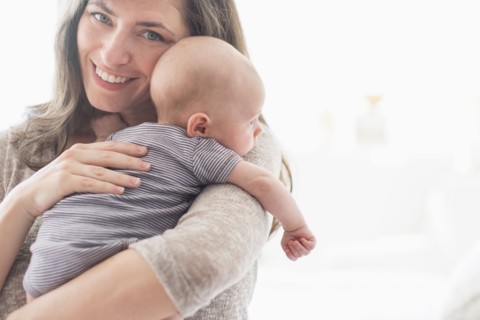 Portrait of smiling mother holding baby boy (2-5 months) on her arm.