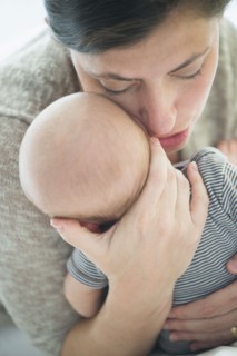 Close up of mother whispering into baby boy's(2-5 months) ear.