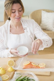 Young woman seasoning salmon.
Photo : Jamie Grill