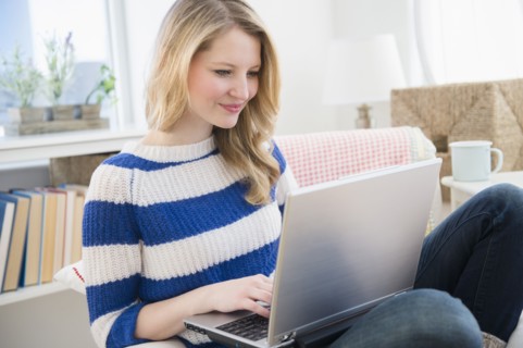 Woman sitting on sofa and using laptop.
Photo : Jamie Grill