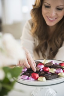 Woman choosing chocolate from cake stand.
Photo : Jamie Grill