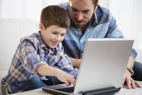 Father working on laptop with his son (8-9) .
Photo : Jamie Grill