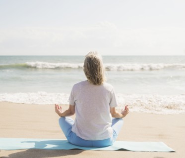 Senior woman practicing yoga on beach.
Photo : Daniel Grill