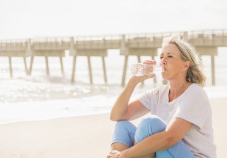 Senior woman drinking water on beach.
Photo : Daniel Grill