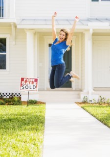 Woman jumping in front of new house.
Photo : Daniel Grill