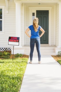 Rear view of woman standing next to for rent sign.
Photo : Daniel Grill