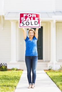 Woman holding for sale sign.
Photo : Daniel Grill