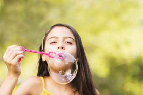 Portrait of girl (8-9) blowing bubbles.
Photo : Daniel Grill