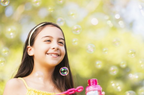 Portrait of girl (8-9) blowing bubbles.
Photo : Daniel Grill