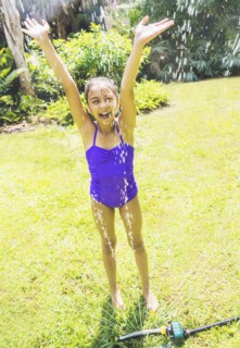 girl (8-9) playing in sprinkler.
Photo : Daniel Grill