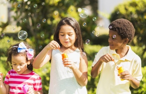 Girls( 4-5, 8-9) and boy (6-7) blowing soap bubble.
Photo : Daniel Grill