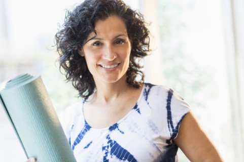 Portrait of smiling woman with yoga mat.