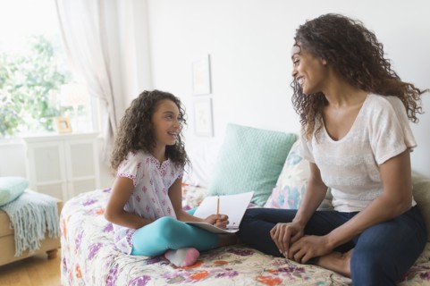 Girl (8-9) using digital tablet on bed.