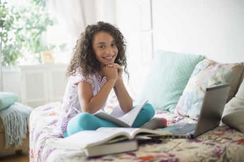 Girl (8-9) studying on bed.