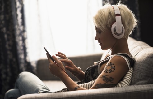 Woman sitting on sofa using digital tablet.