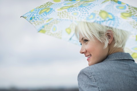 Profile of blonde woman under umbrella.
