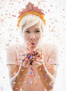 Woman wearing tiara blowing confetti.