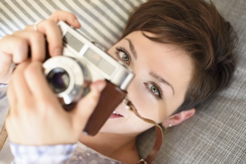 Portrait of young woman holding old fashioned camera.