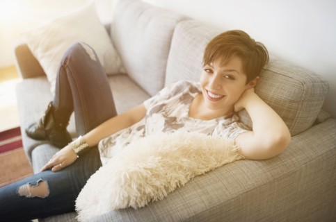 Portrait of smiling woman sitting on sofa.