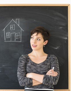 Woman in front of blackboard with house drawing.