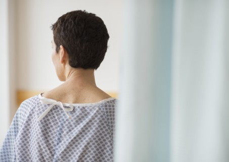 Rear view of senior woman wearing hospital gown.