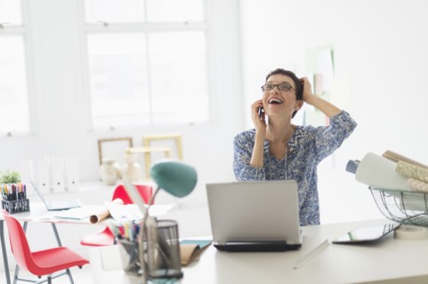 Senior business woman using cell phone in office.