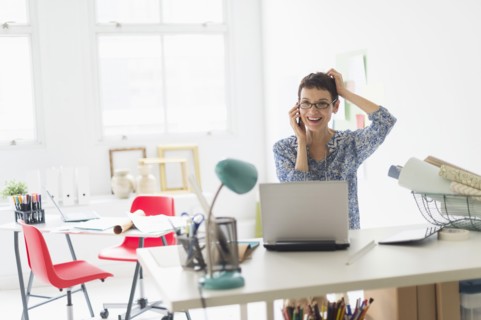 Senior business woman using cell phone in office.