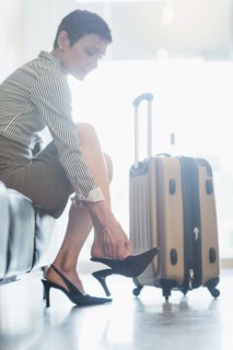Businesswoman at the airport adjusting shoe.