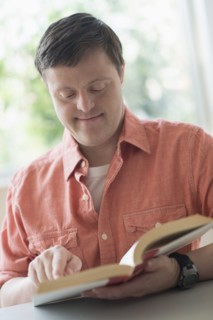 Man with down syndrome reading book.