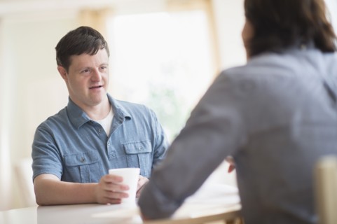 Man with down syndrome talking with care taker.