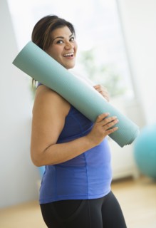 Woman holding exercise mat at gym.