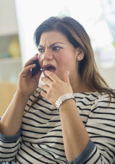 Surprised woman sitting on sofa with mobile phone.