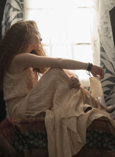 Portrait of stylish woman sitting in window sill.