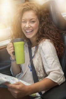 Woman sitting in car with map and disposable cup.