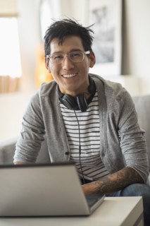 Portrait of man with headphones in front of laptop.