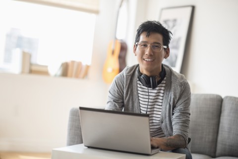 Portrait of man with headphones in front of laptop.